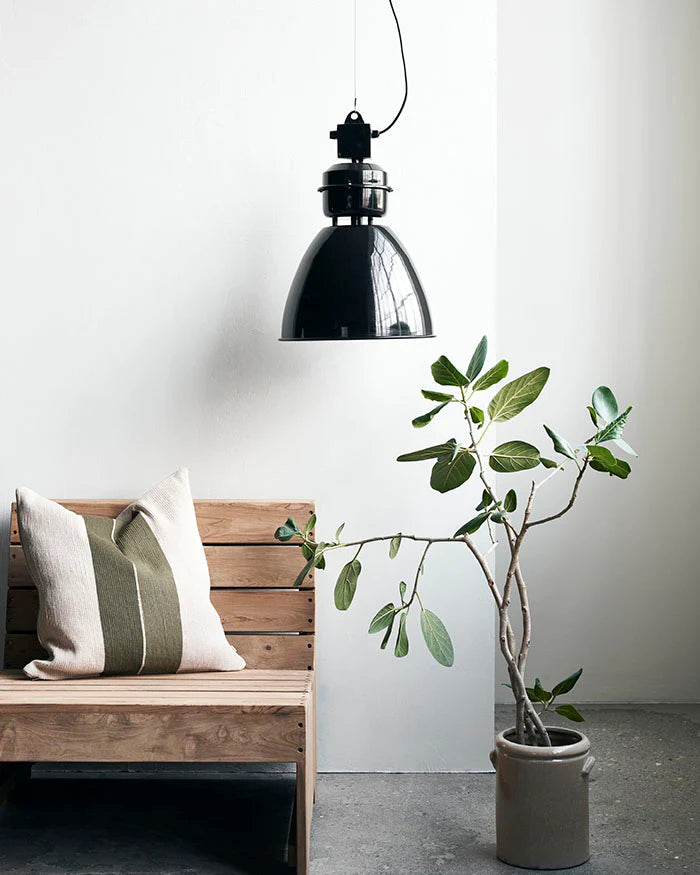 Wooden lounge chair with cushion and a large black metal lamp